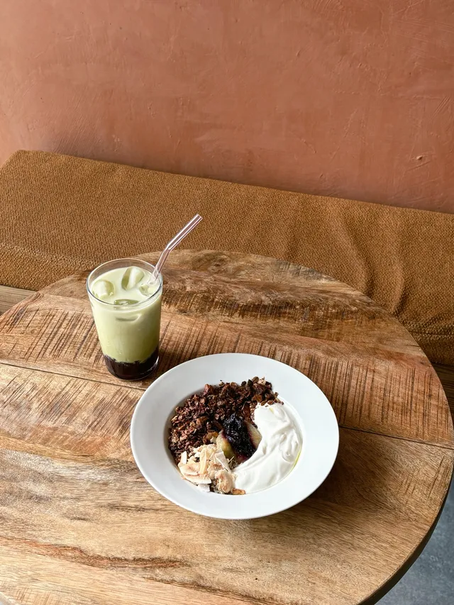 An iced matcha and granola bowl on a wooden table